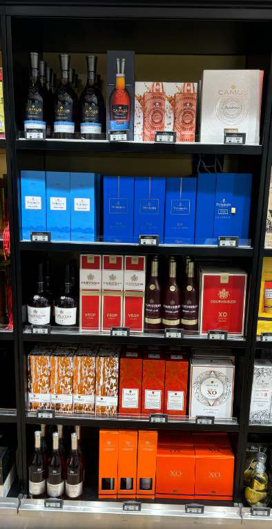 The open Cognac shelf in Paris CDG T1 where Courvoisier is listed alongside other brands