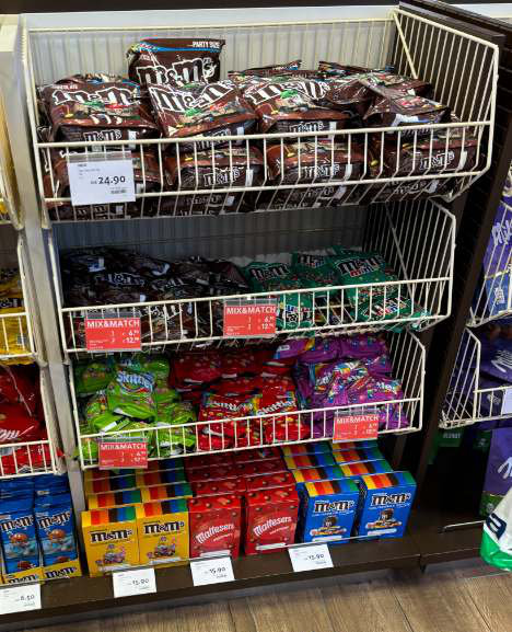 M&M’s in open wire baskets at Amsterdam Schiphol, sharing the fixture with Skittles and Maltesers