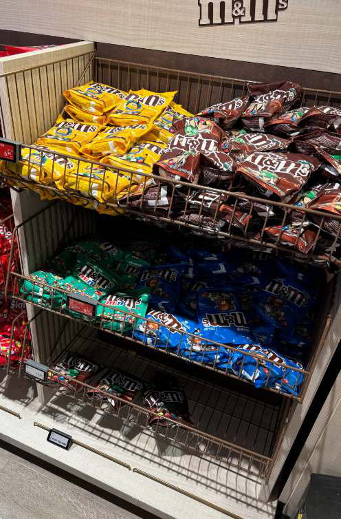 A second M&M’s wire-basket bay at Amsterdam Schiphol with a sparsely stocked lower tier